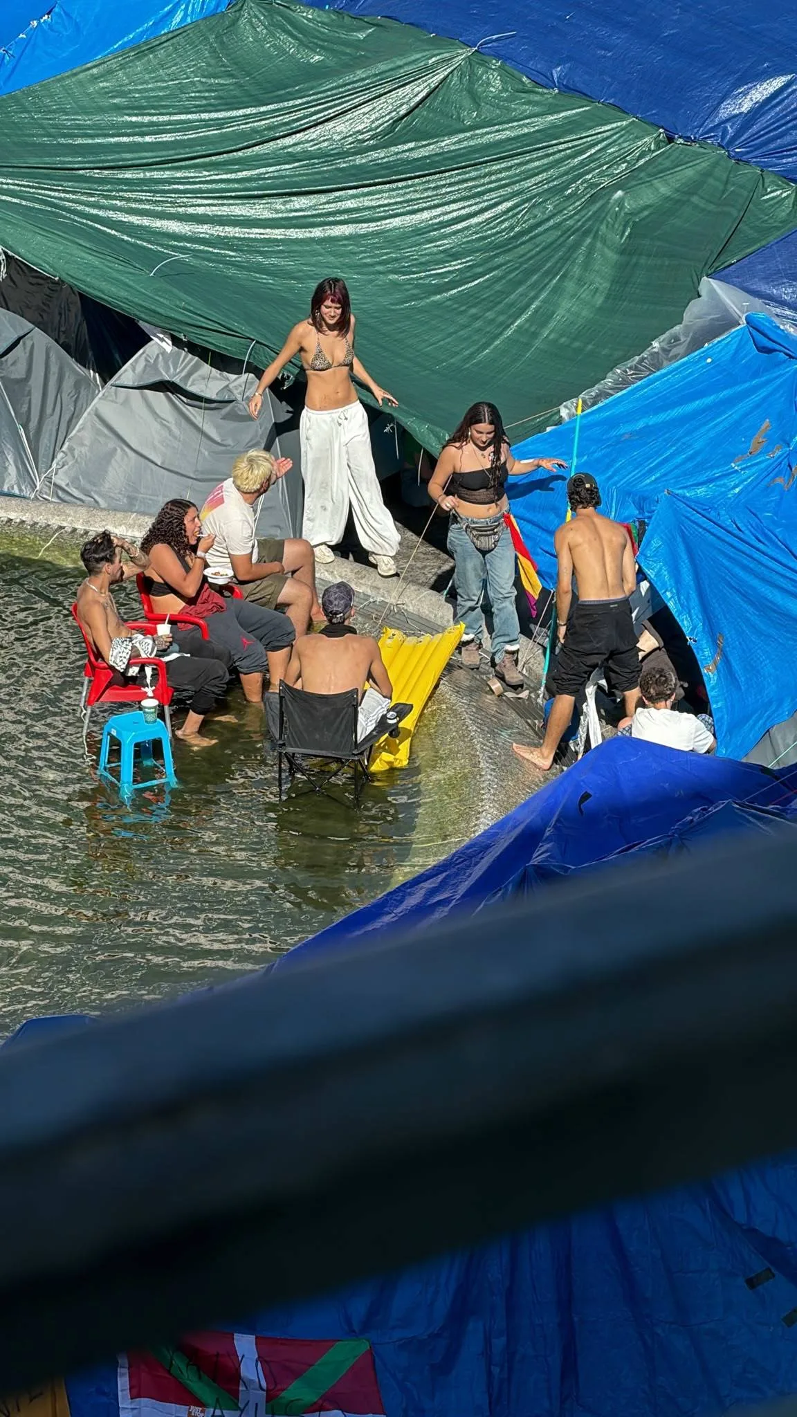 El parque acuático de Sol: los acampados convierten en piscina, con colchonetas incluidas, la fuente de la plaza