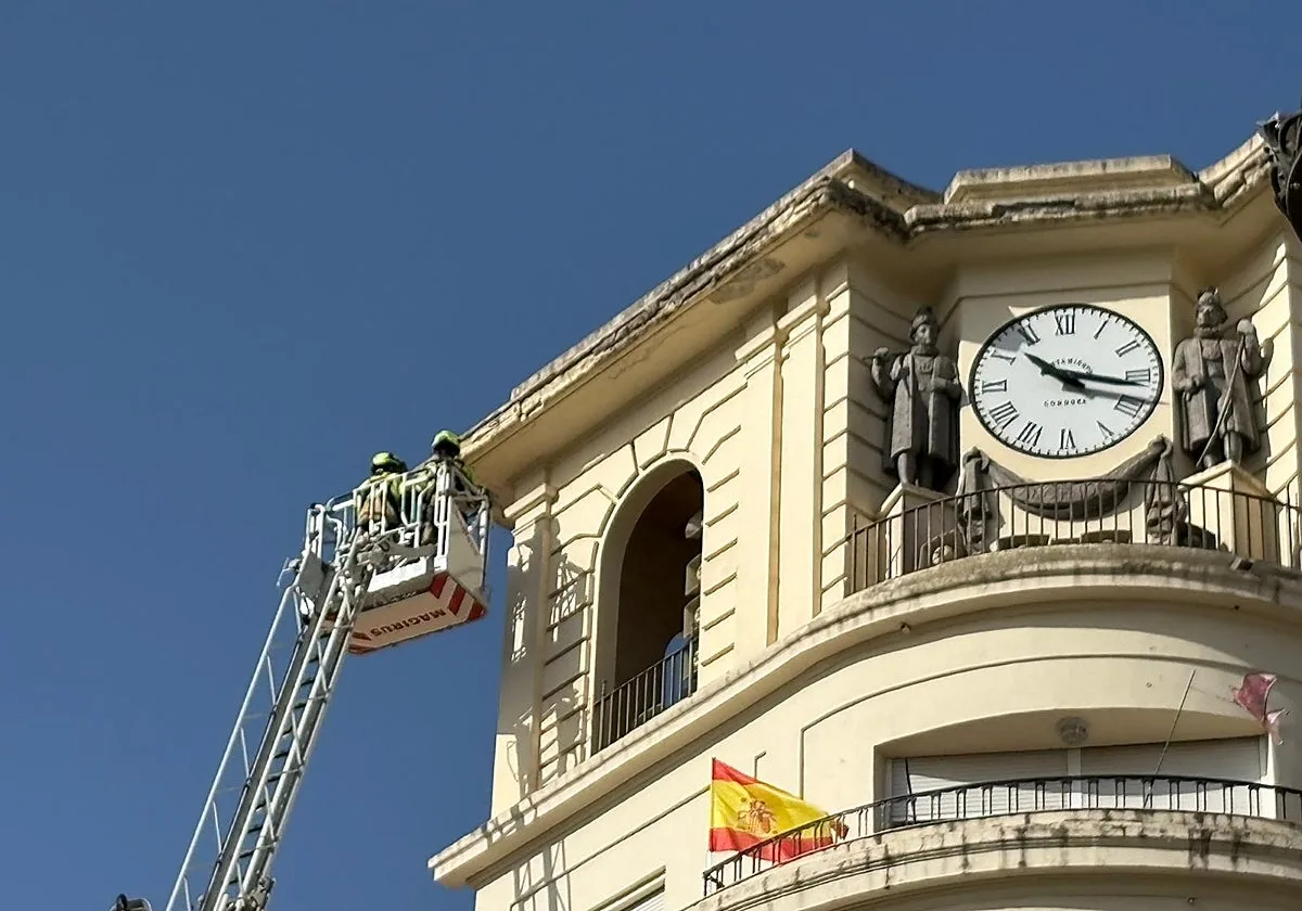 Los bomberos retiran cascotes en mal estado de la cornisa del edificio del reloj de la plaza de las Tendillas