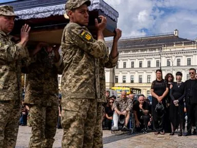 A pregnant soldier mourns her 21-year-old husband at his funeral in Ukraine
